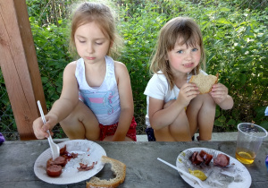 Dziewczynki jedzą pieczoną kiełbaskę